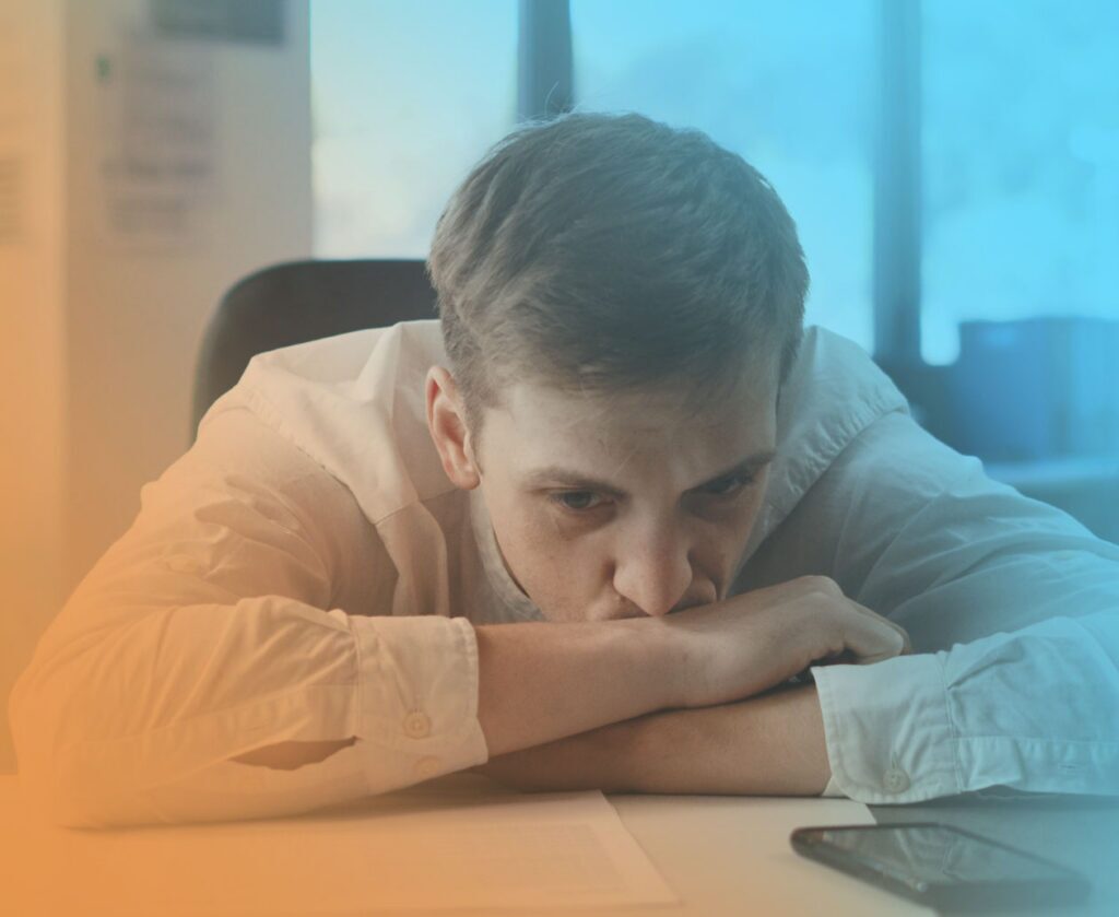 An man experiencing business inefficiency, sulking with his head on his hands.