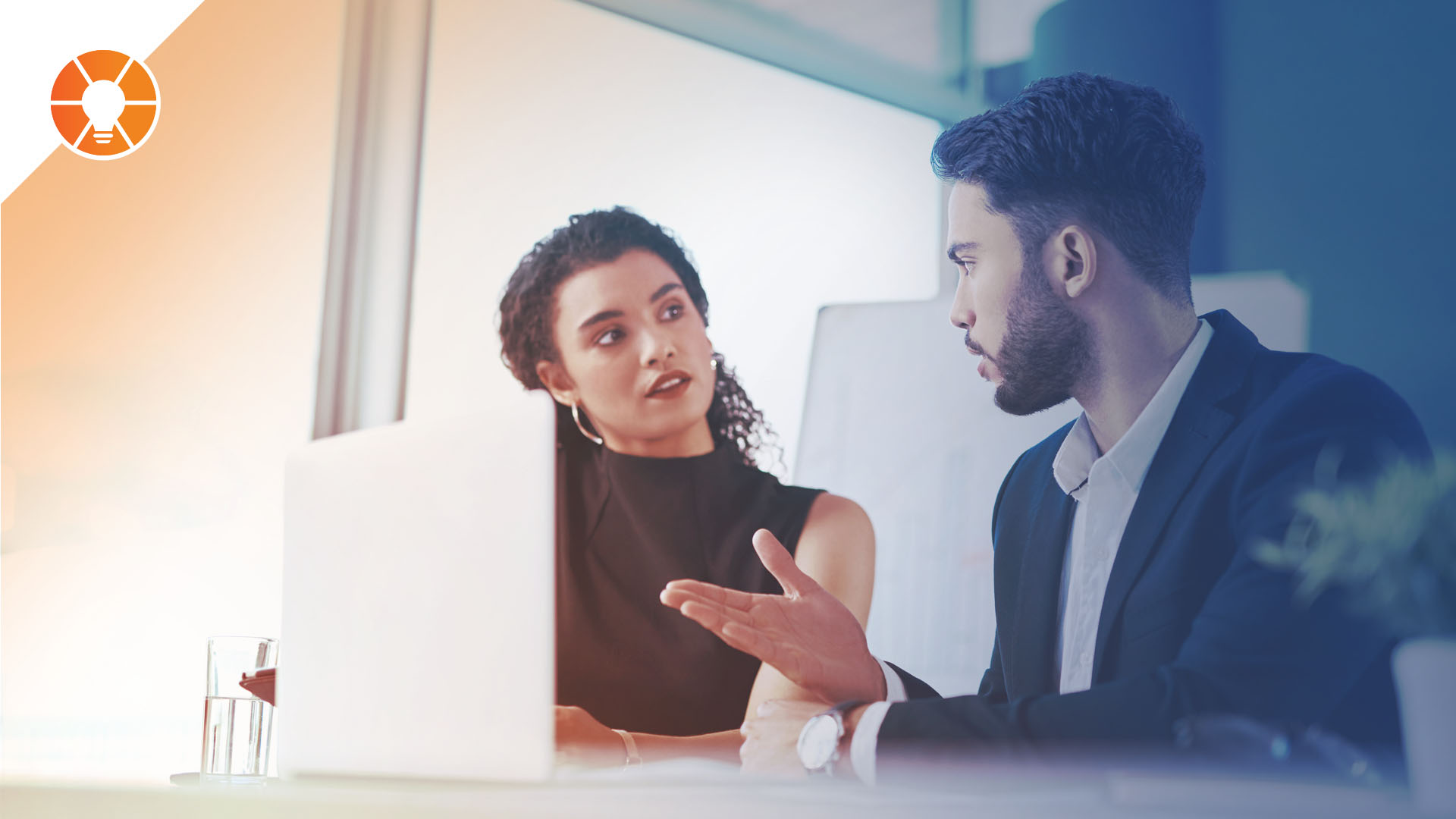 Two people in a discussion, referencing a laptop