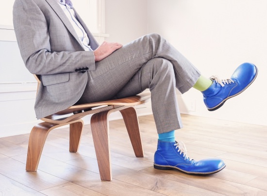 businessman in a suit with clown shoes sitting in a chair - example of promoting the wrong people