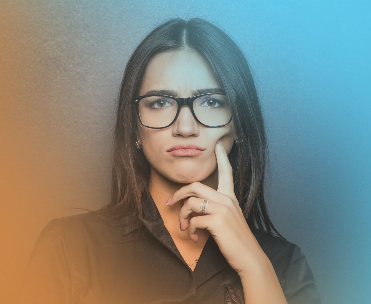 Woman wearing glasses with a skeptical expression, resting her chin on her hand against a blue and orange background.