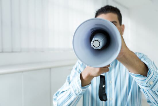 businessman speaking into a megaphone, repeating himself to his employees