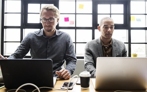Two men working on their computers