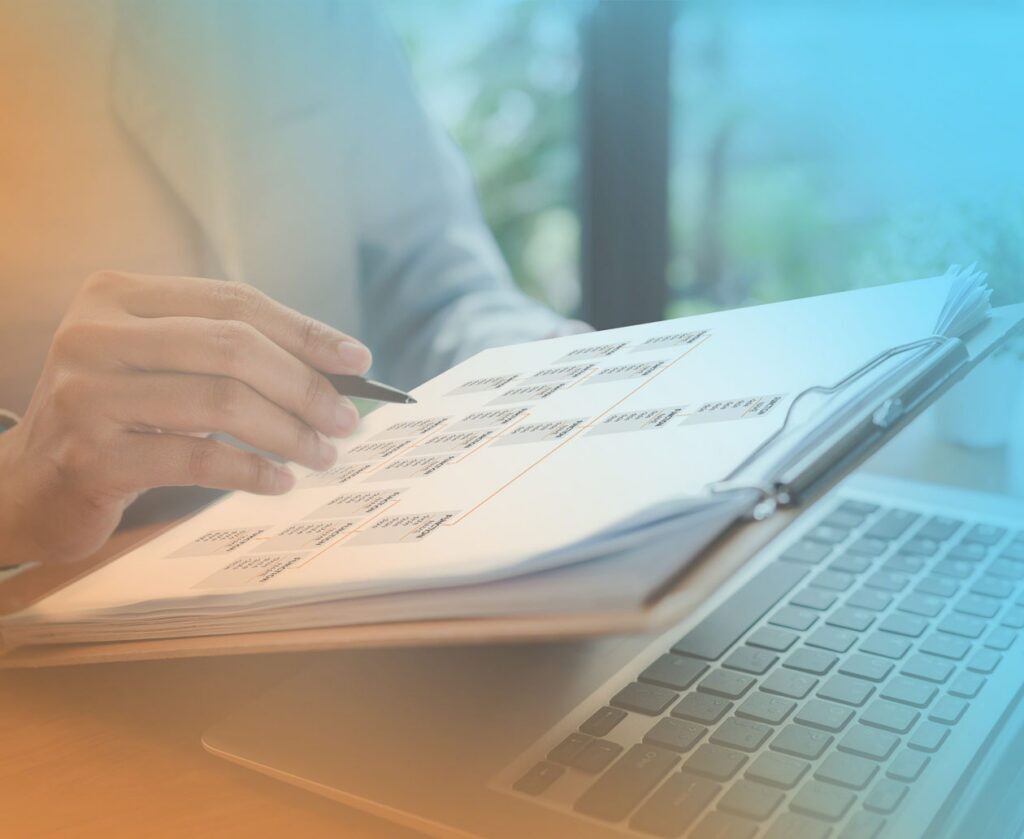 Person reviewing a printed workflow diagram beside a laptop, representing team accountability and shared responsibility.