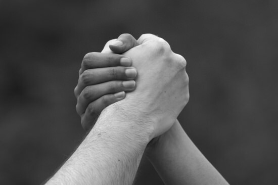 closeup of two people grasping hands to show the power of a positive word