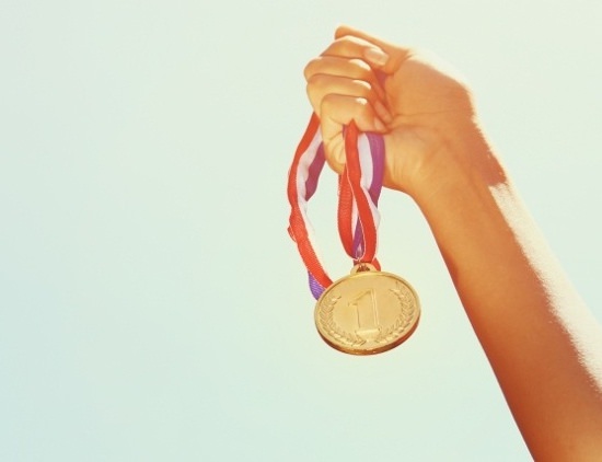 hand holding a gold medal up in the air