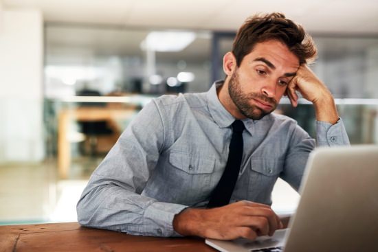 disengaged employee sitting in front of his laptop looking bored