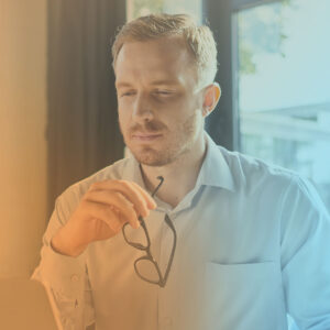 A person with eyes closed and holding glasses while thinking