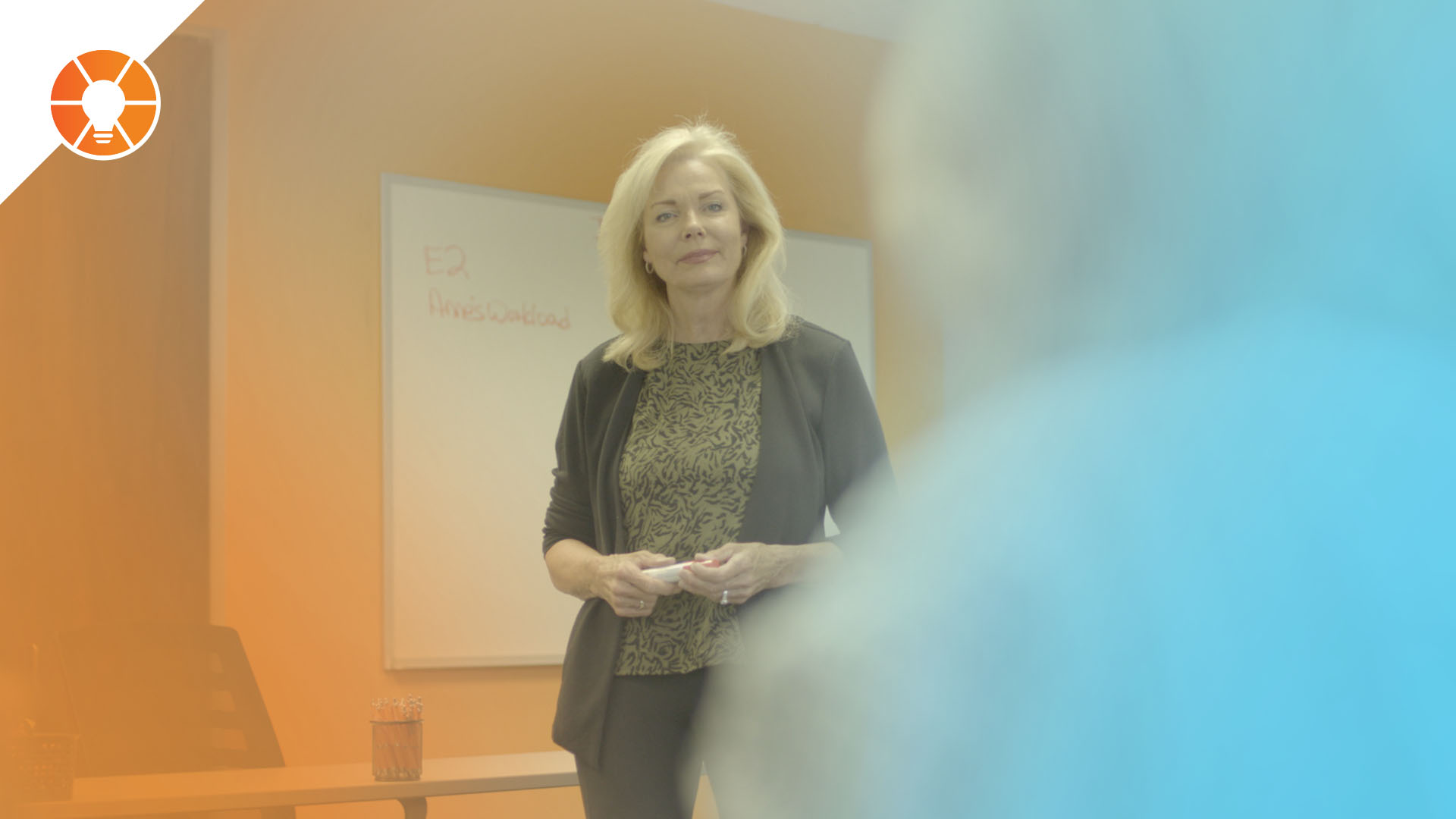 Business leader presenting in a meeting room with a whiteboard, representing EOS concepts of scorecards, individual measurables, and accountability to track performance and align teams.